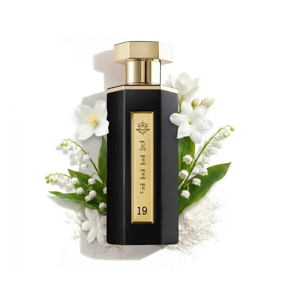 Elegant black perfume bottle with gold accents, surrounded by white flowers and green leaves
